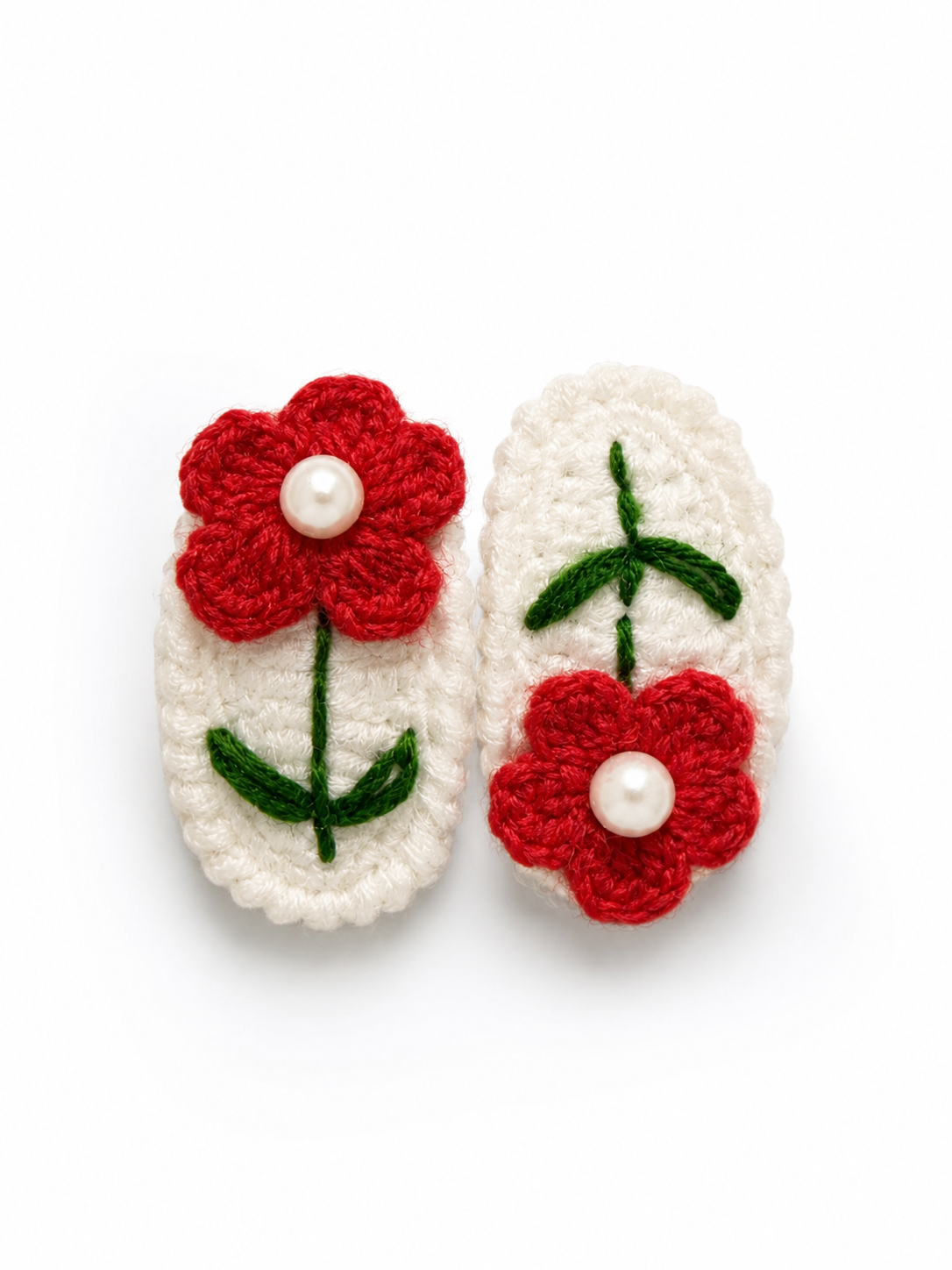 Two white crocheted slipper-shaped accessories with red embroidered flowers and green stems, each with a small white pearl center, shown on a plain white background.